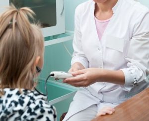 otolaryngologist tests hearing of a girl patient